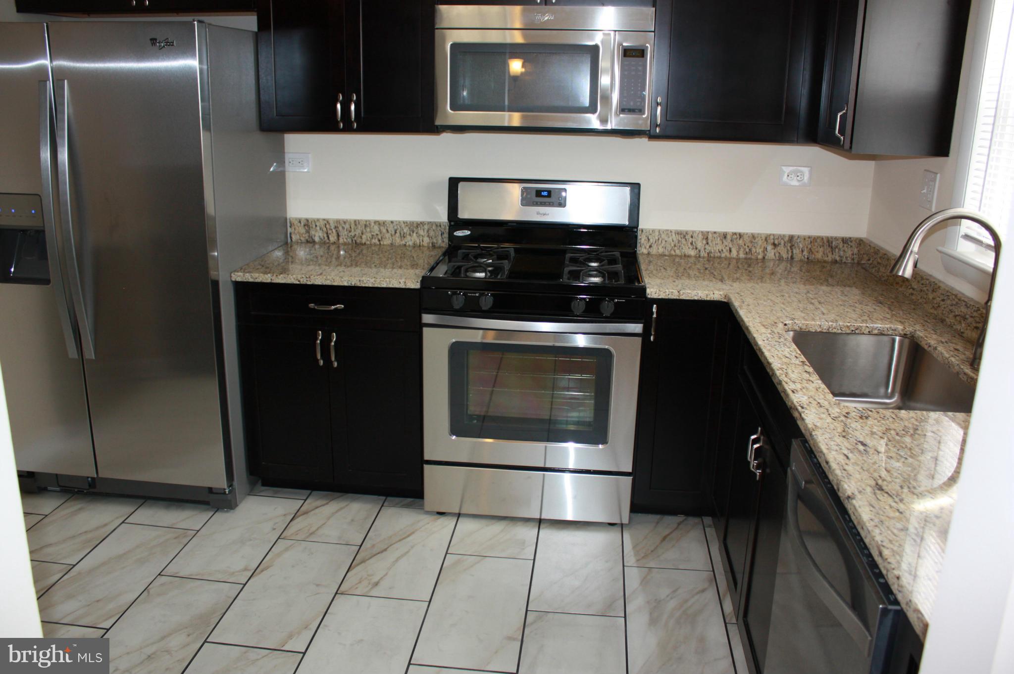 6833 Windsor Mill Road Baltimore, MD 21207 - Photo 9 of 17 a kitchen with granite countertop a refrigerator and a stove