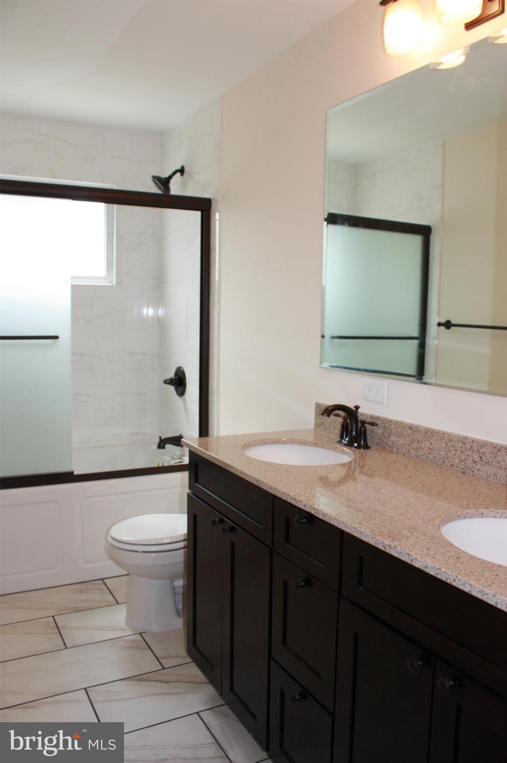6833 Windsor Mill Road Baltimore, MD 21207 - Photo 10 of 17 a bathroom with a granite countertop sink a toilet and mirror