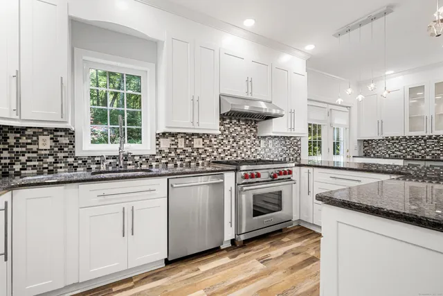 a kitchen with granite countertop white cabinets and white stainless steel appliances