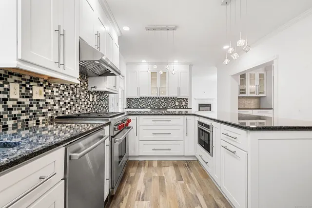 a kitchen with stainless steel appliances granite countertop a sink stove and cabinets