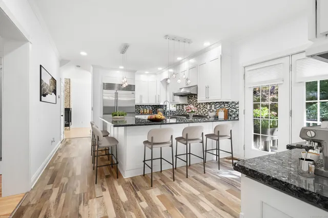 a kitchen with stainless steel appliances granite countertop a refrigerator a stove and white cabinets with wooden floor