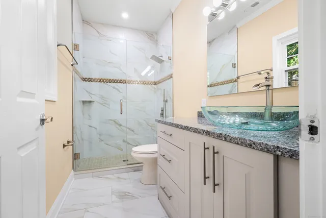 a bathroom with a granite countertop sink a toilet and shower