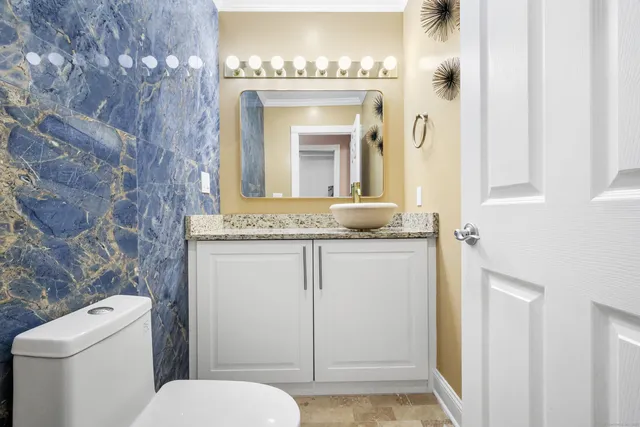 a bathroom with a granite countertop toilet sink and mirror