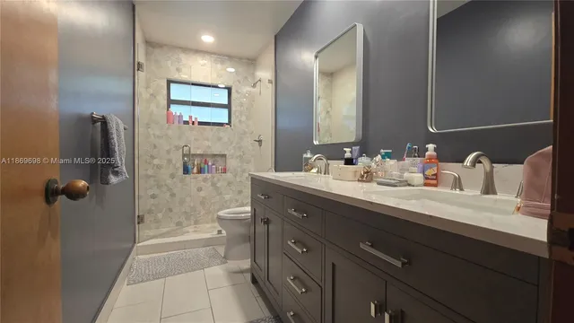 a bathroom with a double vanity sink a toilet and shower