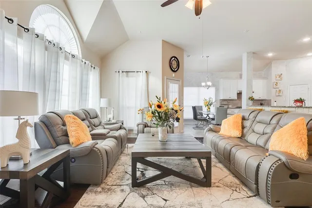 a living room with furniture kitchen view and a large window
