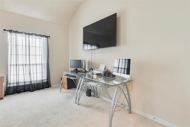 a work room with furniture a flat screen tv and a window