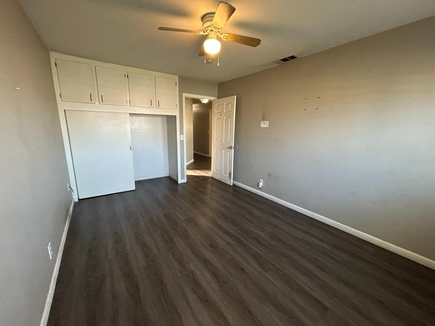 2581 Ballantyne Drive Merced, CA 95341 - Photo 5 of 16 an empty room with wooden floor a ceiling fan and kitchen view