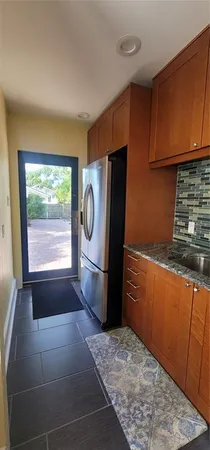 a kitchen with granite countertop a refrigerator a stove top oven cabinetry a sink and a window