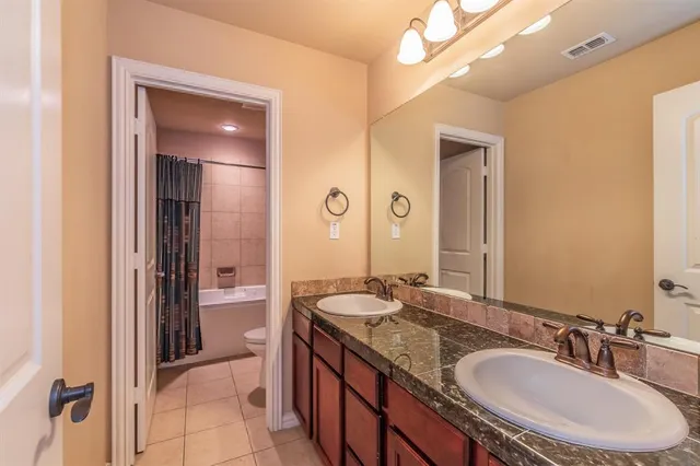 a bathroom with a granite countertop double vanity sink and a mirror