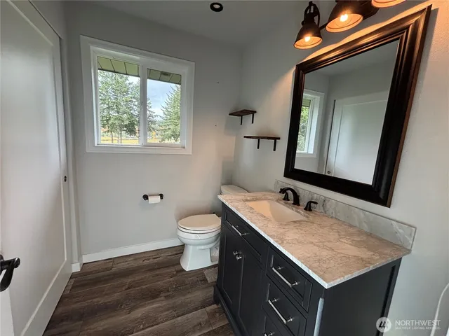 a bathroom with a granite countertop sink toilet a mirror and a window