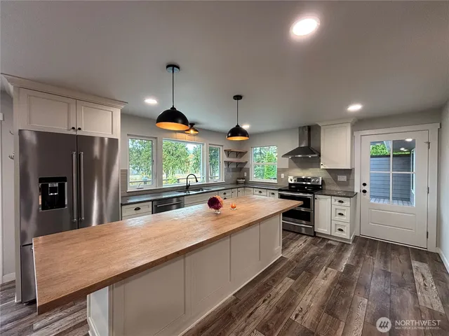 a kitchen with stainless steel appliances granite countertop a sink a stove and a refrigerator
