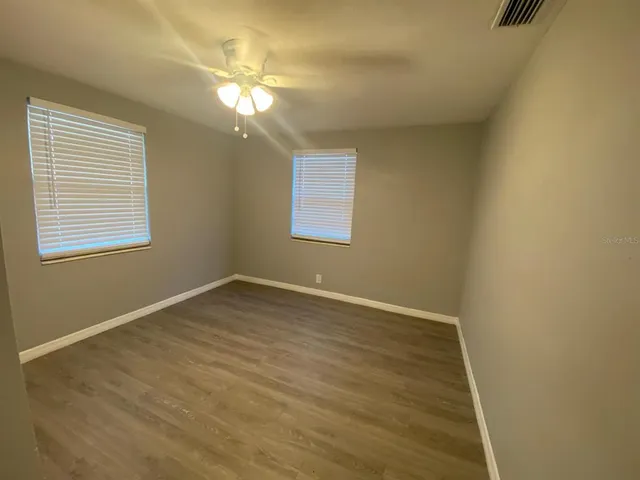 a view of an empty room with wooden floor and a window