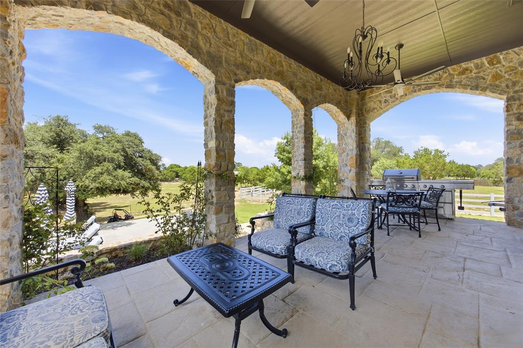 501 Upper Denton Road Weatherford, TX 76085 - Photo 24 of 40 Expansive covered patio featuring stone archways, integrated outdoor kitchen, stone flooring, and an ornamental chandelier