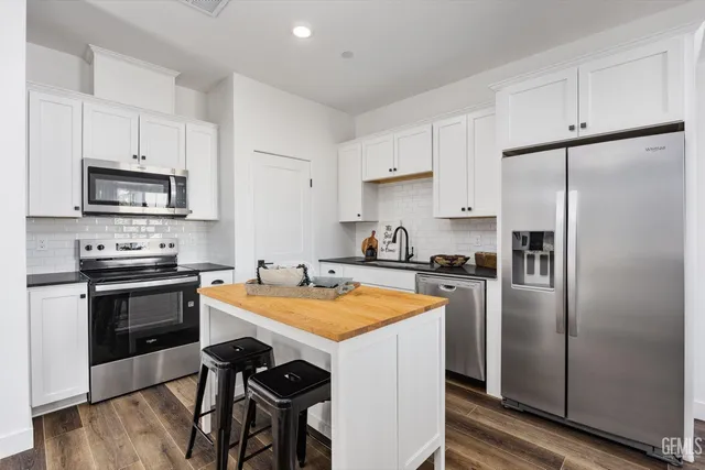 a kitchen with stainless steel appliances a stove a sink a refrigerator a microwave and cabinets