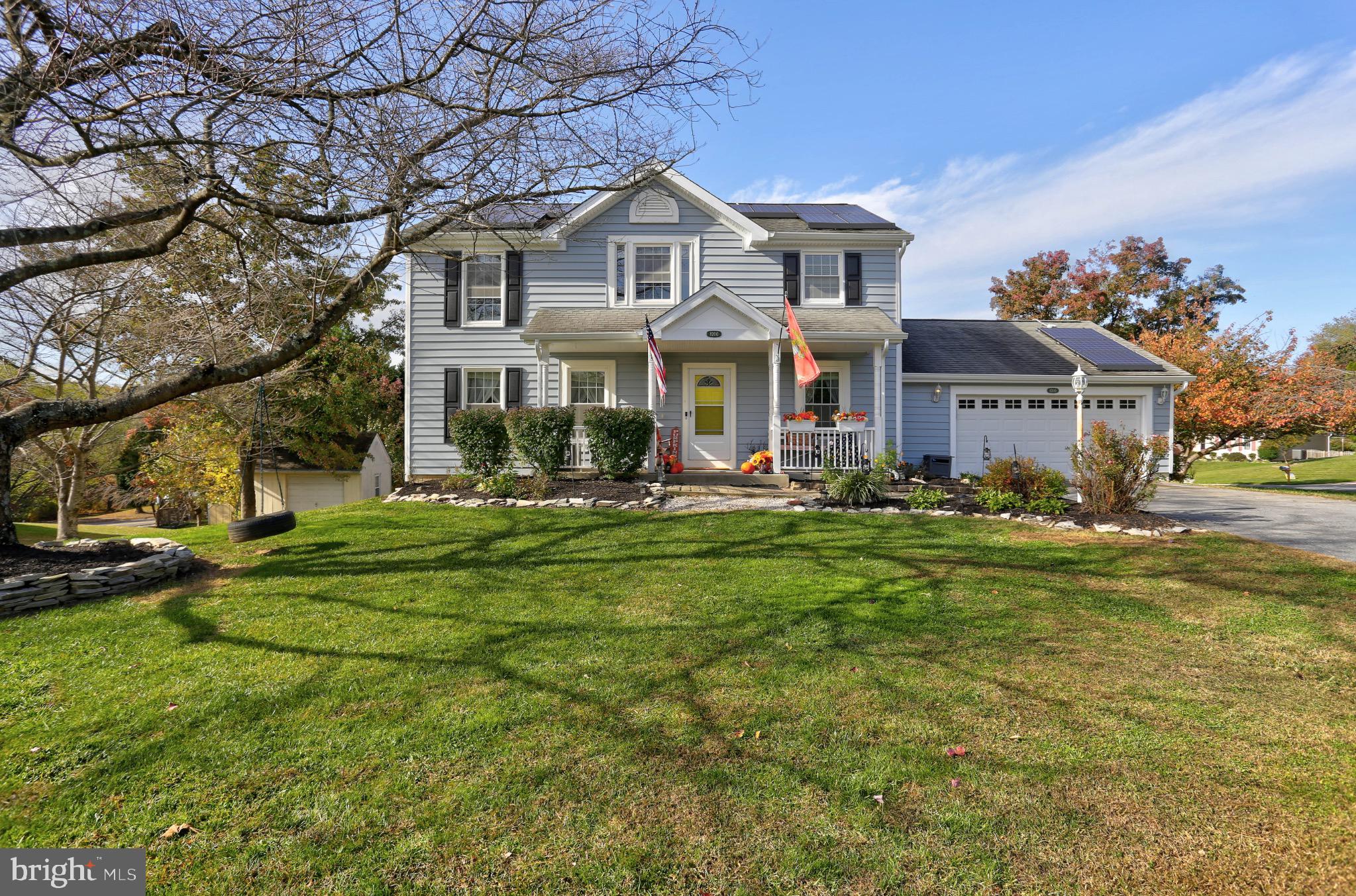 a front view of a house with garden and trees