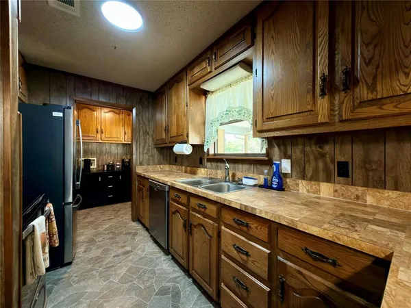 a kitchen with stainless steel appliances granite countertop sink a refrigerator and green cabinets