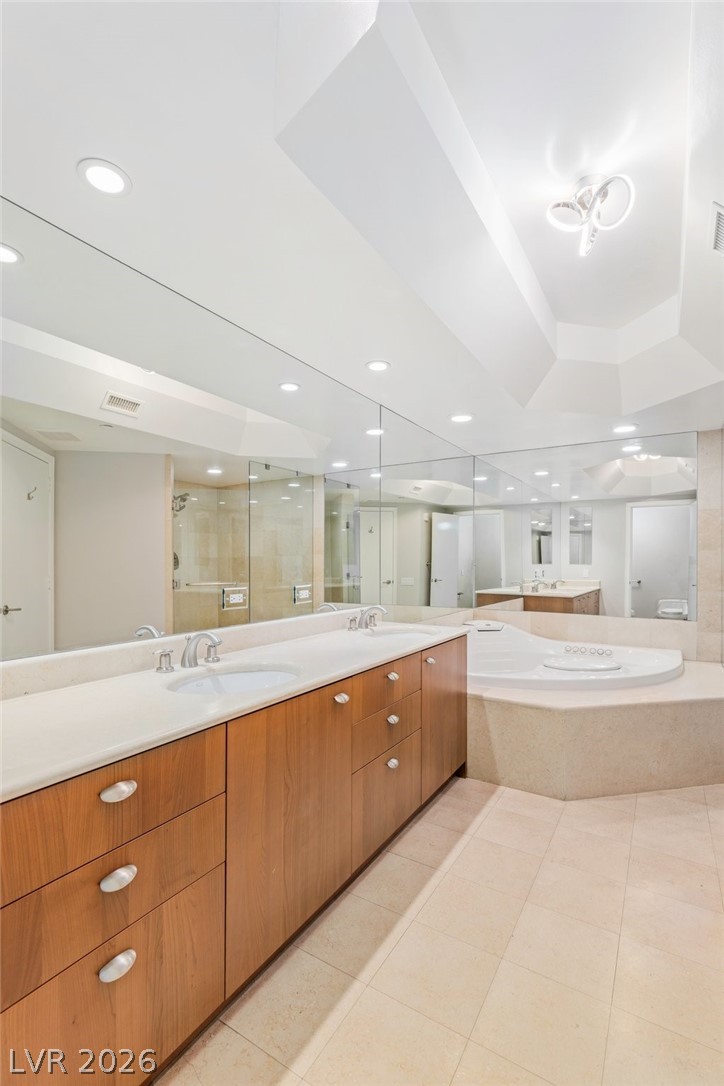 2777 Paradise Road, Unit 901 Las Vegas, NV 89109 - Photo 14 of 27 Full bath with visible vents, double vanity, a sink, a stall shower, and a garden tub