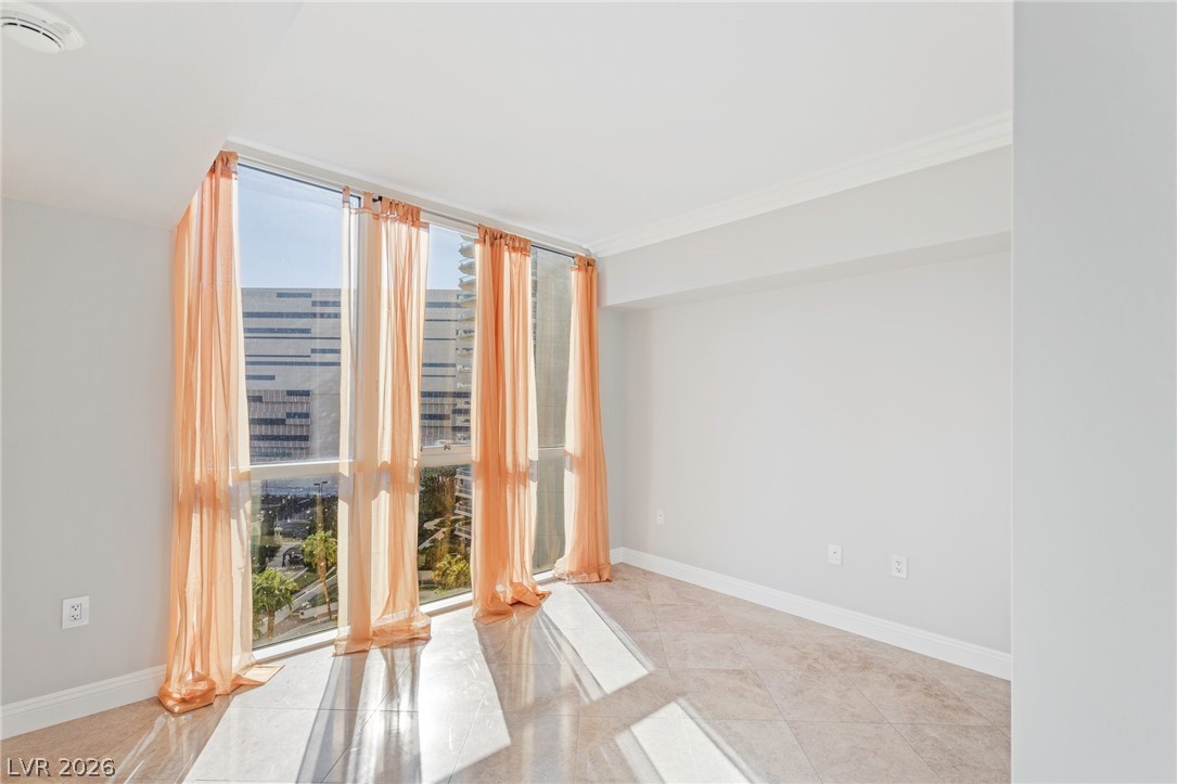 2777 Paradise Road, Unit 901 Las Vegas, NV 89109 - Photo 19 of 27 Tiled spare room featuring baseboards, floor to ceiling windows, ornamental molding, and a healthy amount of sunlight