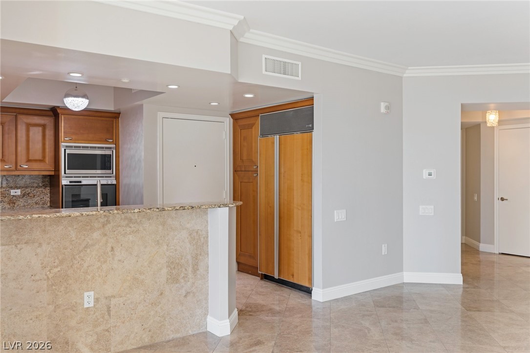 2777 Paradise Road, Unit 901 Las Vegas, NV 89109 - Photo 24 of 27 Kitchen with visible vents, crown molding, baseboards, brown cabinets, and built in appliances