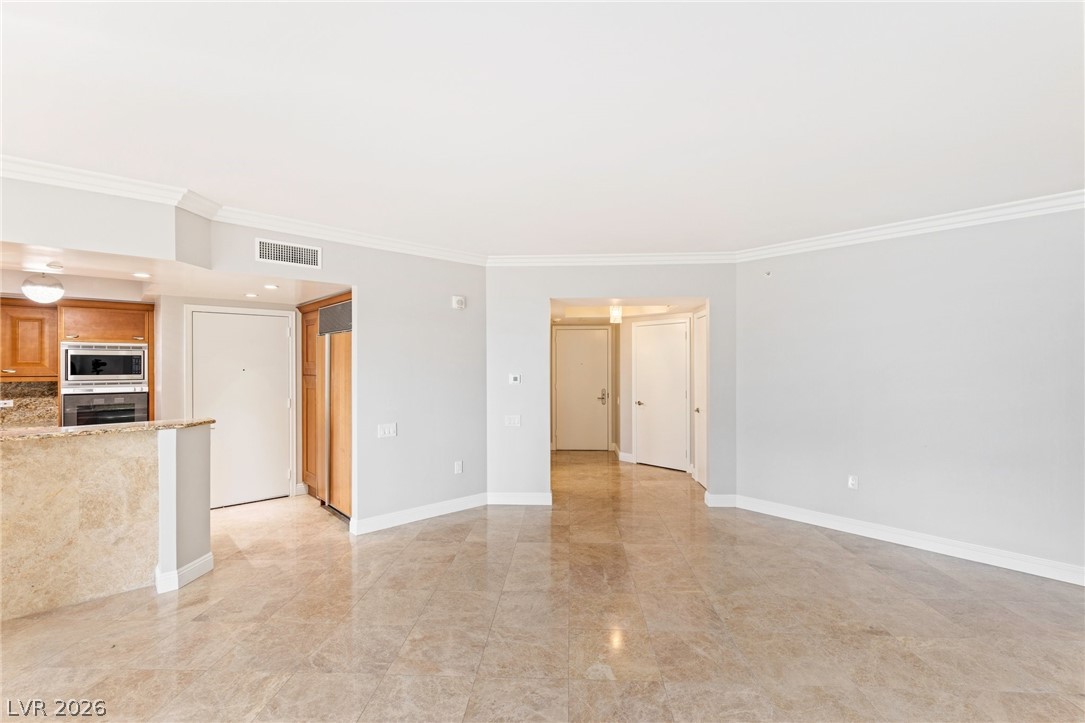 2777 Paradise Road, Unit 901 Las Vegas, NV 89109 - Photo 5 of 27 Unfurnished living room featuring baseboards, ornamental molding, and visible vents