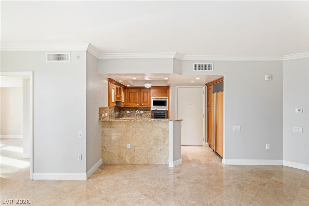 2777 Paradise Road, Unit 901 Las Vegas, NV 89109 - Photo 6 of 27 Kitchen featuring baseboards, visible vents, brown cabinetry, and appliances with stainless steel finishes