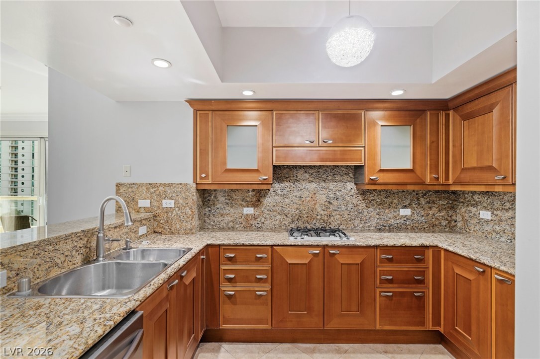 2777 Paradise Road, Unit 901 Las Vegas, NV 89109 - Photo 7 of 27 Kitchen featuring backsplash, a sink, brown cabinetry, and under cabinet range hood