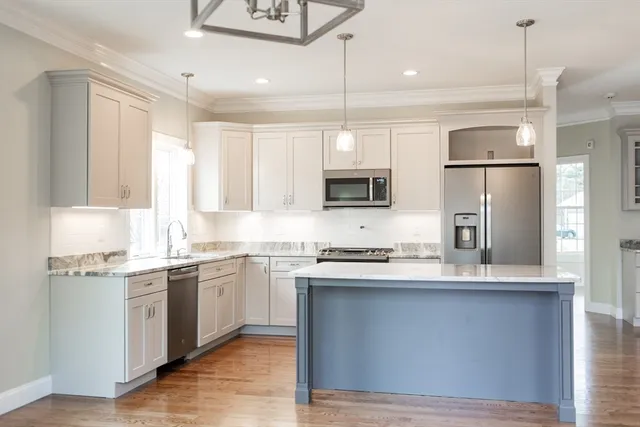 a kitchen with stainless steel appliances granite countertop a refrigerator a sink dishwasher a stove and white cabinets with wooden floor