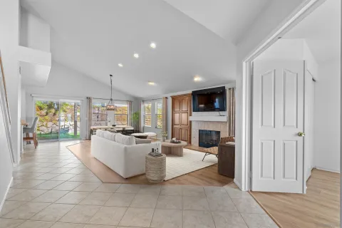 a living room with furniture a fireplace and a dining table with kitchen view