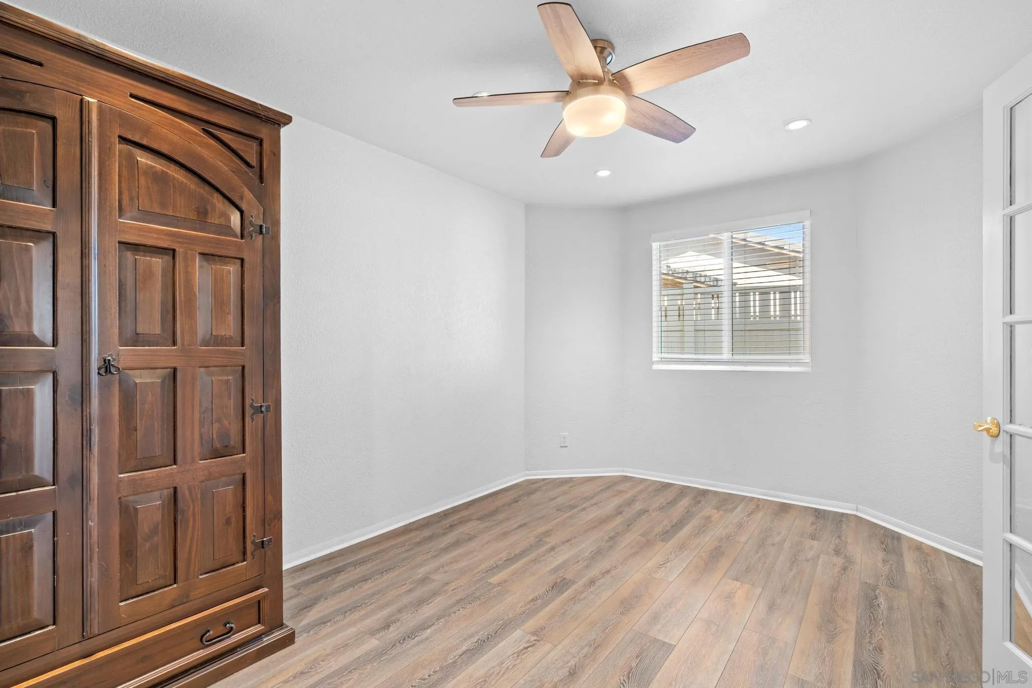 2028 Boulders Road Alpine, CA 91901 - Photo 25 of 56 an empty room with wooden floor ceiling fan and windows