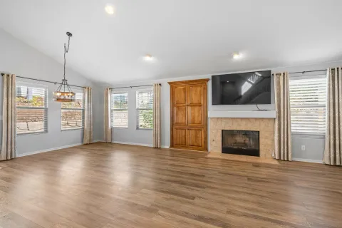 a view of an empty room with fireplace and wooden floor