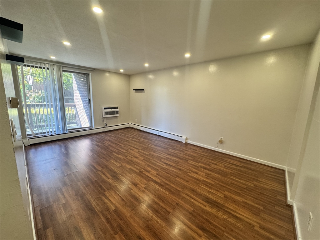 144 Kenrick Street, Unit 12 Boston, MA 02135 - Photo 5 of 11 an empty room with wooden floor and windows