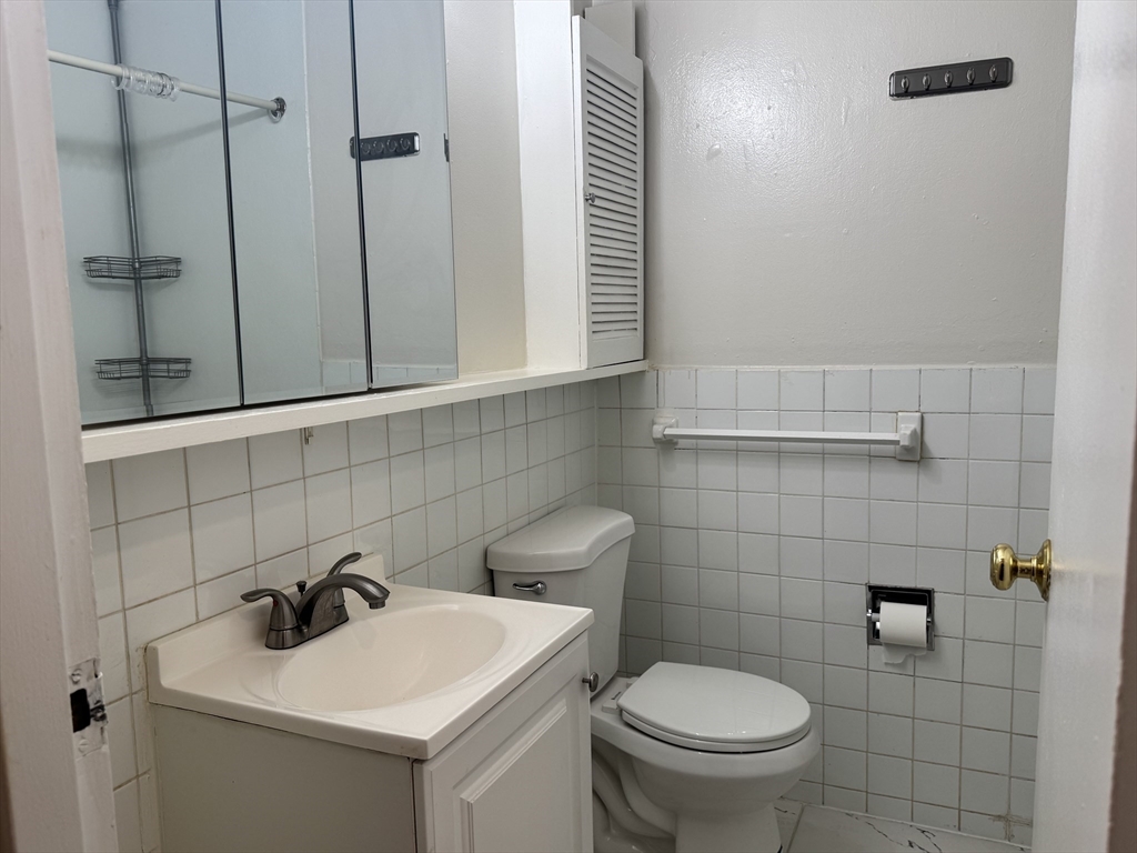 144 Kenrick Street, Unit 12 Boston, MA 02135 - Photo 9 of 11 a bathroom with a toilet sink and mirror