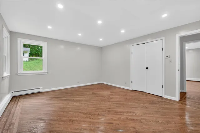 a view of an empty room with wooden floor and a window