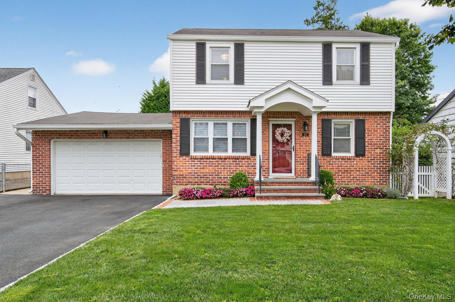 437 Andrews Road Mineola, NY 11501 - Photo 1 of 1 Colonial-style house featuring a garage, brick siding, and driveway