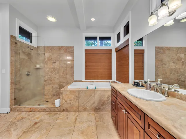 a spacious bathroom with a granite countertop sink a toilet a mirror and shower