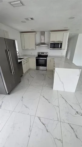 a kitchen with granite countertop a refrigerator and a stove top oven