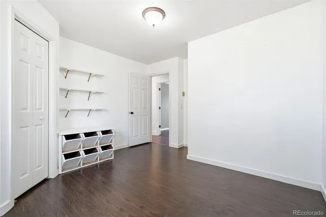 a view of an empty room with wooden floor and windows