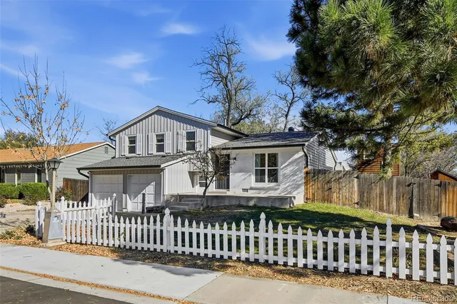 a view of a white house with a large window and wooden fence