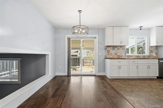 a kitchen with stainless steel appliances granite countertop a stove top oven a sink dishwasher and white cabinets with wooden floor