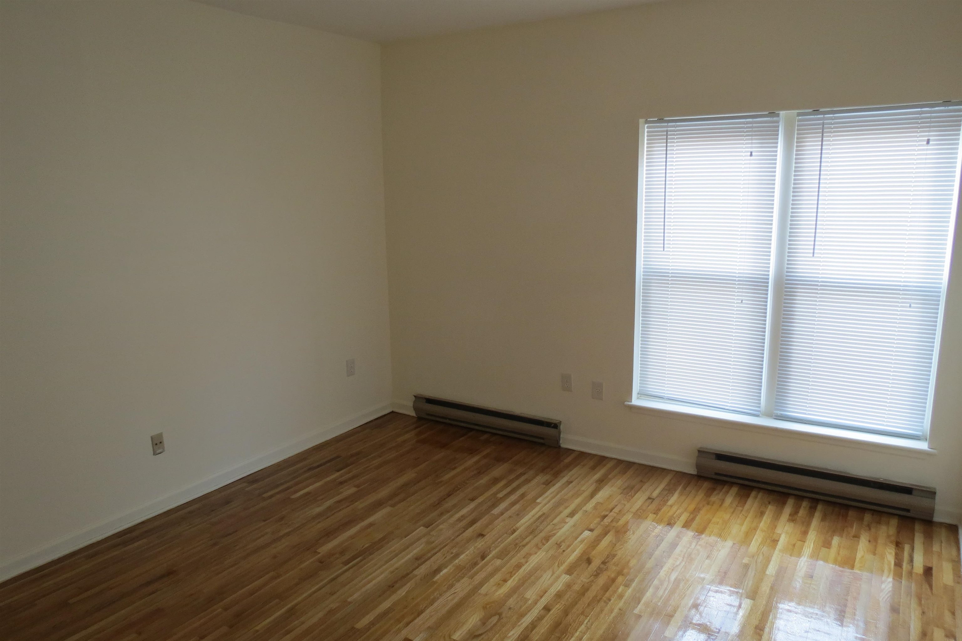 533 Monroe Street, Unit 1D Hoboken, NJ 07030 - Photo 6 of 13 an empty room with wooden floor and windows