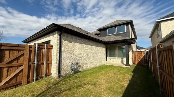 a view of backyard with brick wall and a large tree