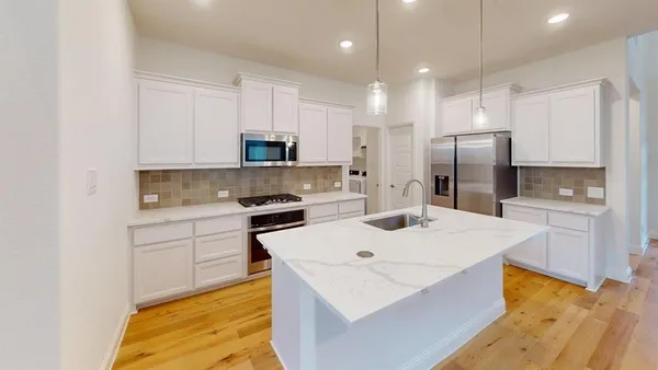 a kitchen with kitchen island a sink stainless steel appliances and white cabinets