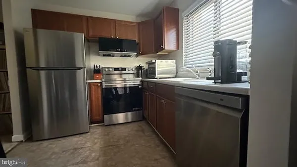 a kitchen with stainless steel appliances granite countertop a refrigerator a stove a sink and a microwave