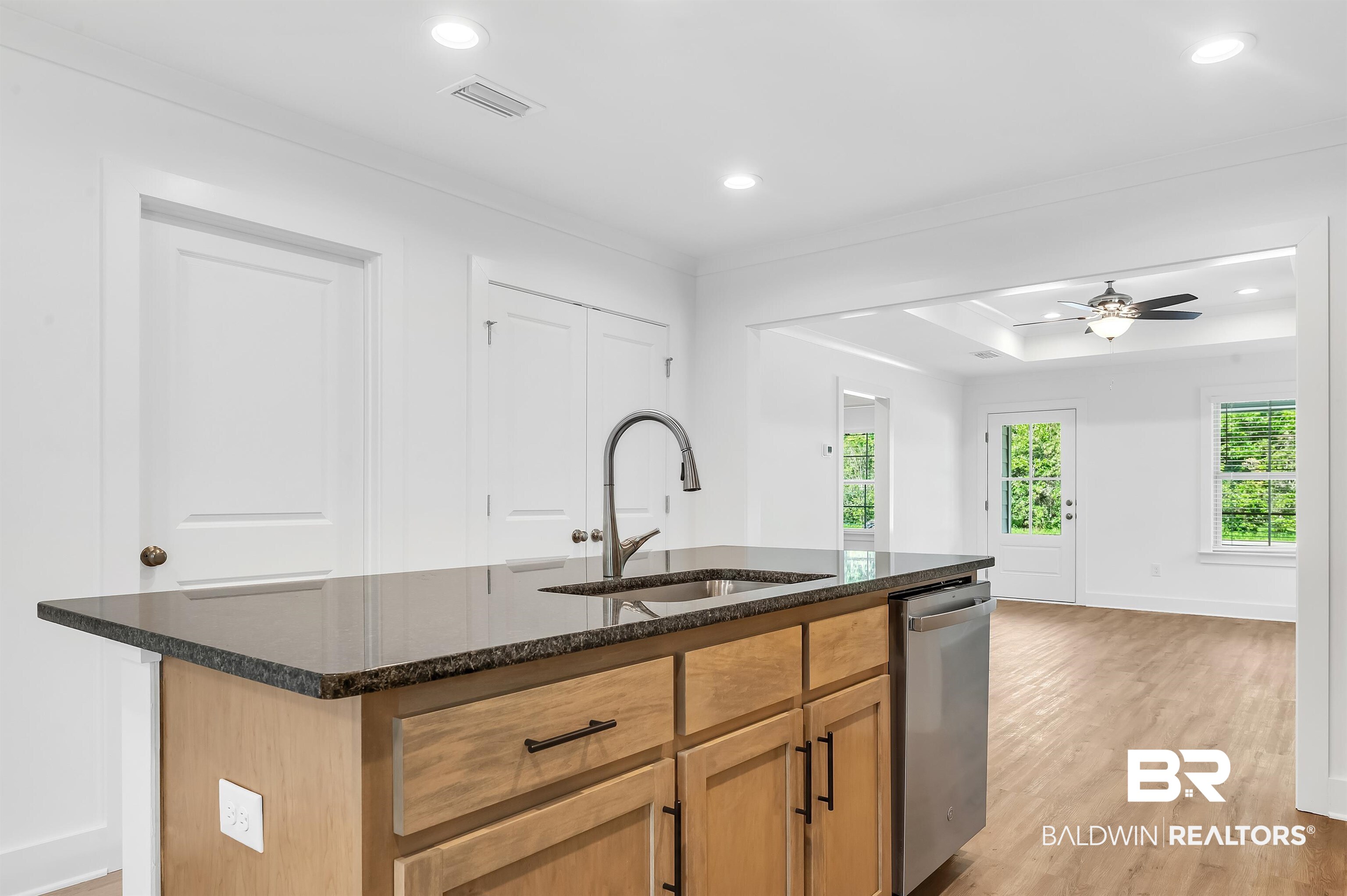 22045 8th Street Silverhill, AL 36576 - Photo 16 of 39 Kitchen featuring a sink, dishwasher, dark stone countertops, light wood-style floors, and a center island with sink