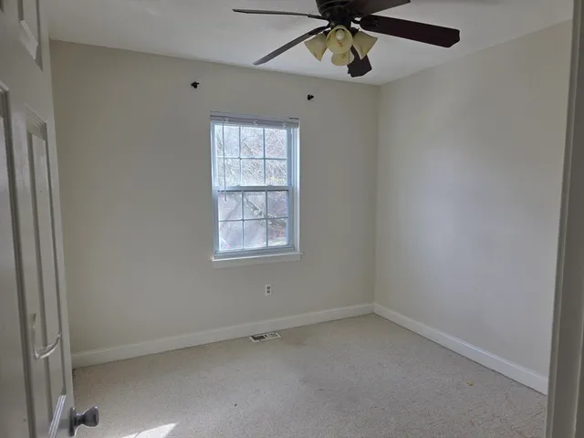 an empty room with a window and a fan
