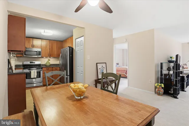 a kitchen with stainless steel appliances kitchen island granite countertop a refrigerator a stove a sink a dining table and chairs with wooden floor
