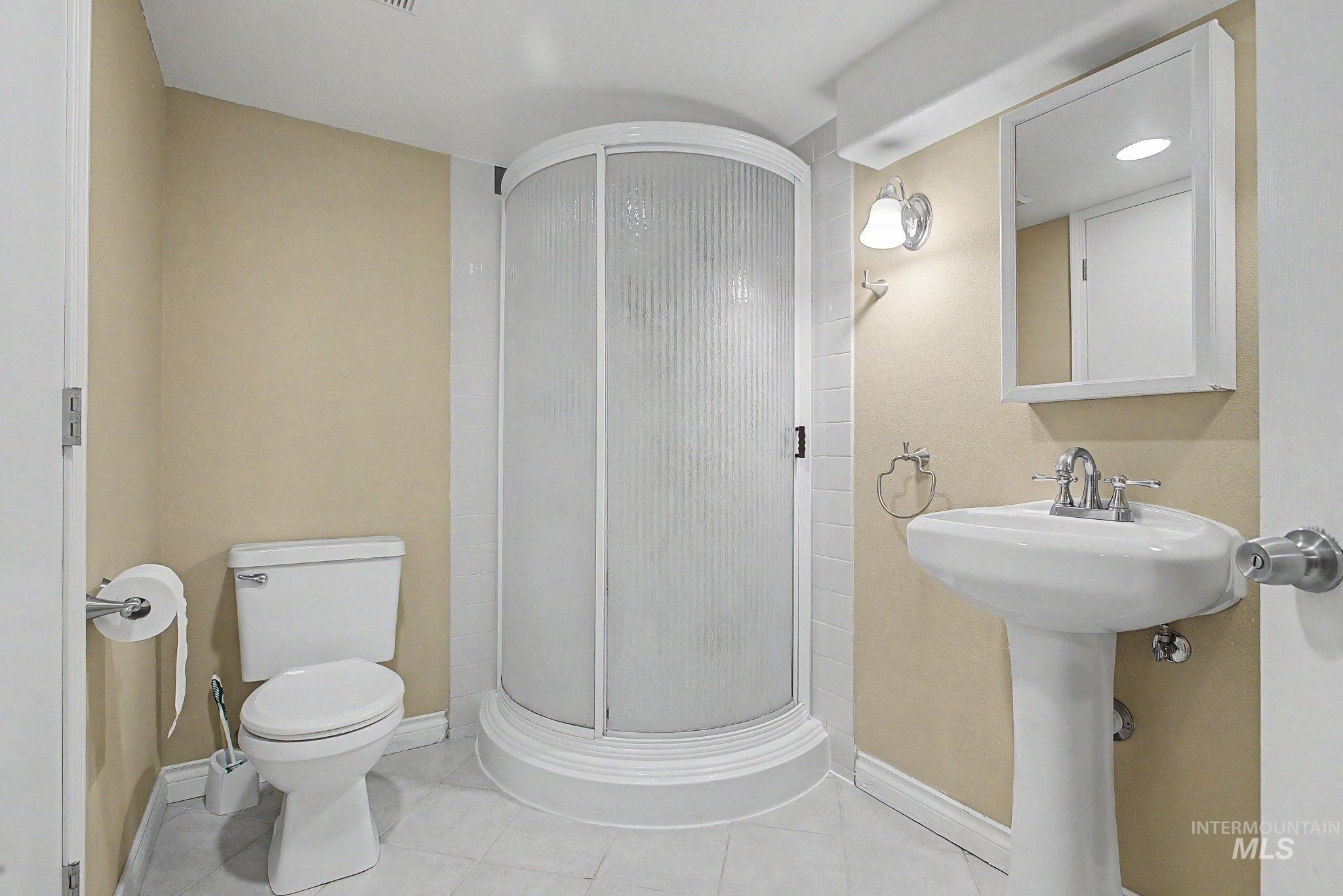 3314 6th Street Lewiston, ID 83501 - Photo 36 of 50 Bathroom featuring a curved shower enclosure with textured glass, a white pedestal sink with chrome faucet, a wall-mounted medicine cabinet, and light-toned wall paint