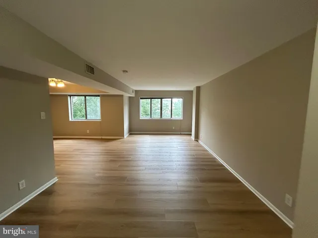 a view of an empty room with window and wooden floor