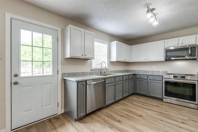 a kitchen with stainless steel appliances granite countertop a stove a sink and a microwave