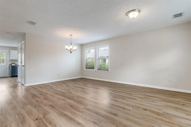 an empty room with wooden floor cabinet and windows